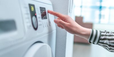 Housewife operates clothes dryer
